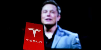 Red Tesla logo with blurred person in background