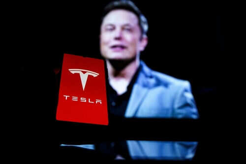 Red Tesla logo with blurred person in background