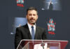 A man in a suit speaking at a podium during a ceremony at TCL Chinese Theatre