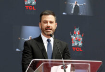 A man in a suit speaking at a podium during a ceremony at TCL Chinese Theatre