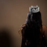 A woman with long hair wearing a sparkling crown, viewed from behind