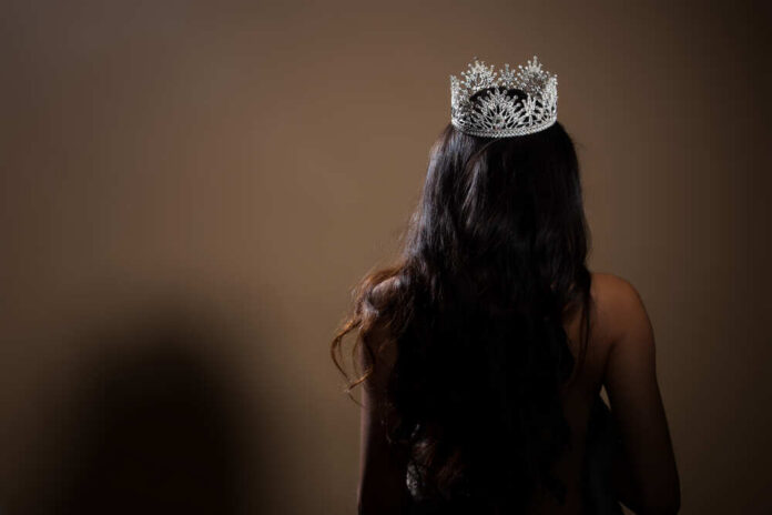 A woman with long hair wearing a sparkling crown, viewed from behind