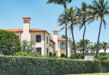 A luxurious house surrounded by palm trees and lush greenery