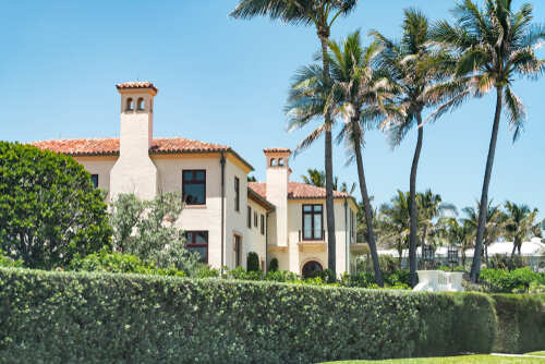 A luxurious house surrounded by palm trees and lush greenery