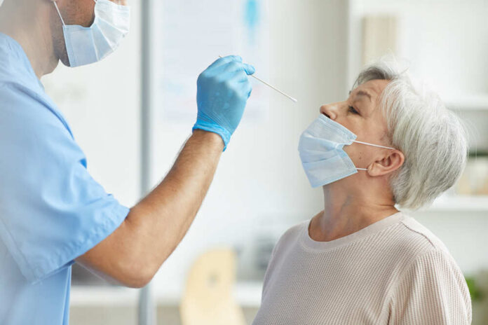 Healthcare worker administering a nasal swab test to an elderly woman
