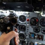 A hand holding a cockpit control device in an aircraft cockpit