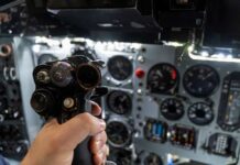 A hand holding a cockpit control device in an aircraft cockpit