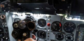 A hand holding a cockpit control device in an aircraft cockpit