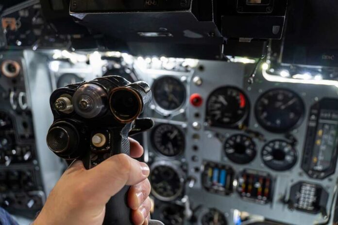 A hand holding a cockpit control device in an aircraft cockpit
