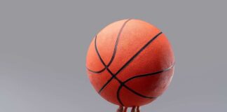 A hand holding an orange basketball against a gray background