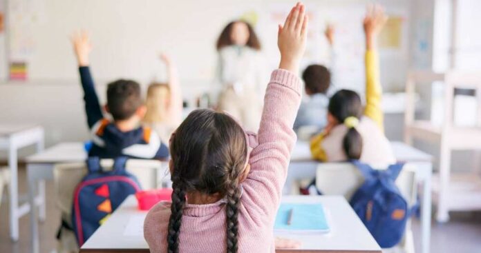 Students in a classroom raising their hands to answer a question