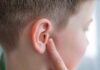 Child touching their ear with a concerned expression