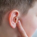 Hearing Restored Without Implants — Miracle Treatment! Child touching their ear with a concerned expression