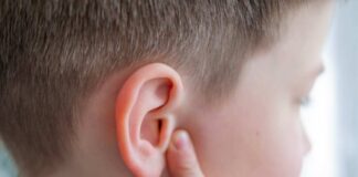 Child touching their ear with a concerned expression