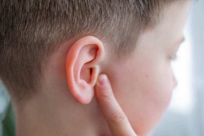 Child touching their ear with a concerned expression