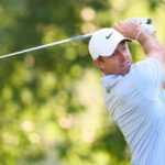 A golfer in mid-swing on a lush green course