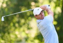 A golfer in mid-swing on a lush green course