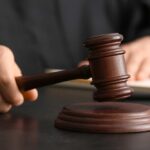 A judge's hand holding a gavel above a wooden block
