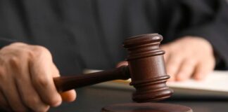 A judge's hand holding a gavel above a wooden block