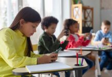 Children in a classroom focused on their smartphones