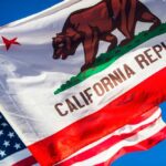 California Republic flag waving alongside the American flag against a blue sky
