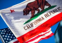 California Republic flag waving alongside the American flag against a blue sky