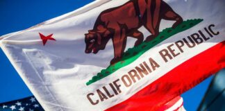 California Republic flag waving alongside the American flag against a blue sky