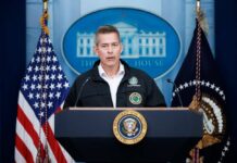 Government official speaking at a podium in the White House briefing room