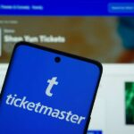 Mobile phone displaying the Ticketmaster app with event details in the background