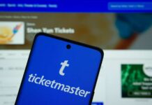 Mobile phone displaying the Ticketmaster app with event details in the background