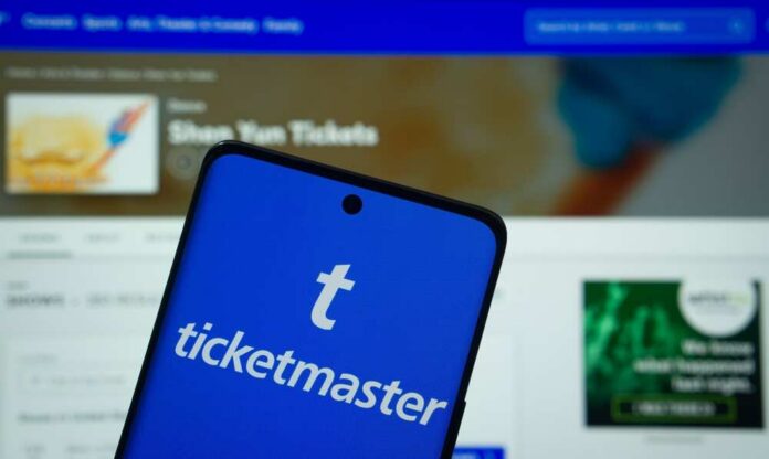 Mobile phone displaying the Ticketmaster app with event details in the background