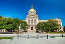 Front view of a government building with a golden dome and surrounding greenery