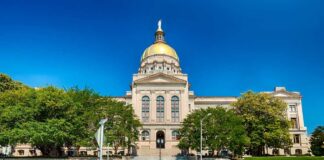 Front view of a government building with a golden dome and surrounding greenery