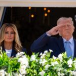 Donald Trump saluting while Melania Trump stands beside him at a public event