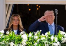 Donald Trump saluting while Melania Trump stands beside him at a public event