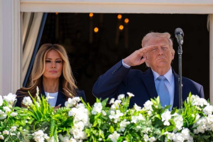 Donald Trump saluting while Melania Trump stands beside him at a public event