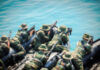 Soldiers in camouflage gear on a boat preparing for a mission