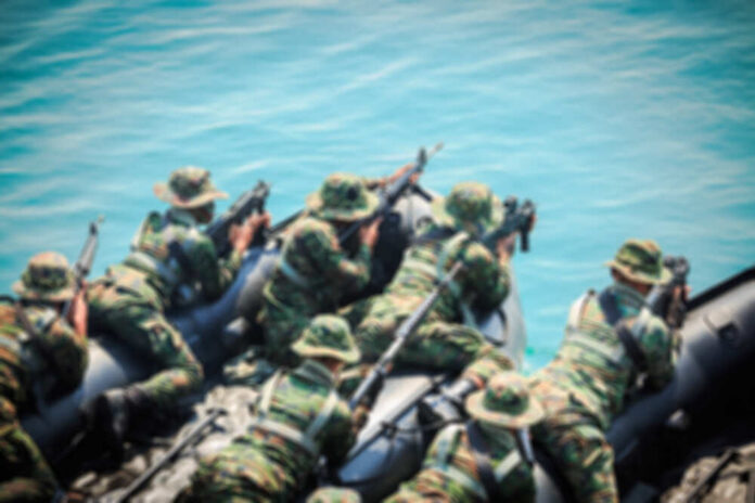 Soldiers in camouflage gear on a boat preparing for a mission