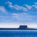 Submarine Strike Shocker—Iran’s Fleet Crippled! A submarine partially submerged in the ocean under a cloudy sky