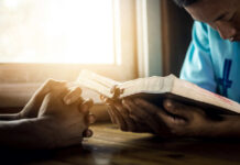 Two individuals engaged in prayer with a Bible