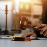 Judge's hand holding a wooden gavel above a sound block