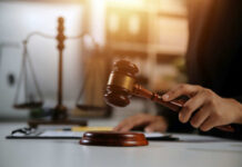 Judge's hand holding a wooden gavel above a sound block