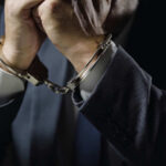 Businessperson in suit with hands cuffed together