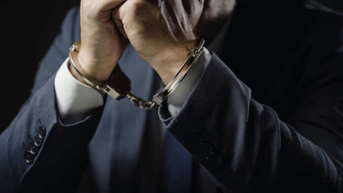Businessperson in suit with hands cuffed together