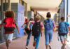 Children with backpacks running in a school corridor