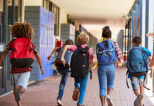 Children with backpacks running in a school corridor
