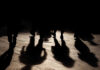 Silhouettes of people walking, casting shadows on the ground
