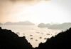 A tranquil view of islands and boats on calm water during sunset