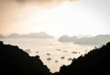 A tranquil view of islands and boats on calm water during sunset