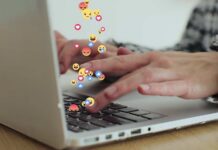 Hands typing on a laptop with floating emojis above